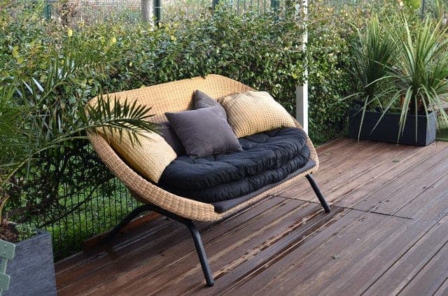 Image shows a sofa and plants giving privacy on a porch. 