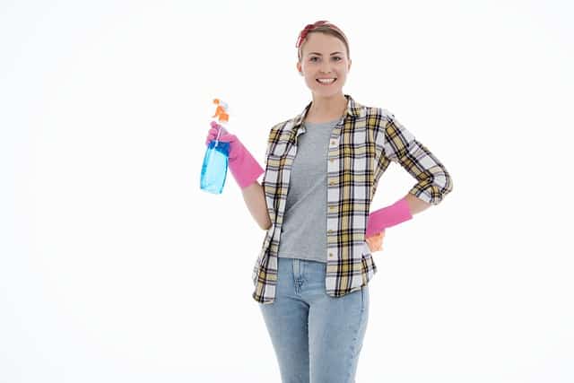 Smiling woman with cleaning gloves and plastic spray bottle.  