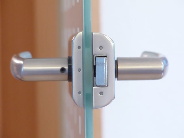 Door knob and lock in metal on glassdoor. 
