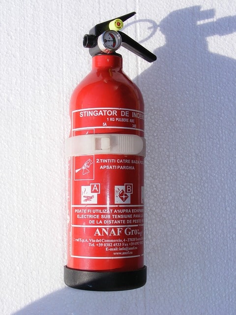 Fire extinguisher hanging on a white wall.